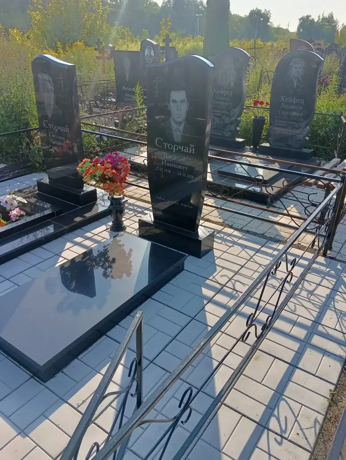 Памятник с полированной гранитной надгробной плитой и металлической оградой