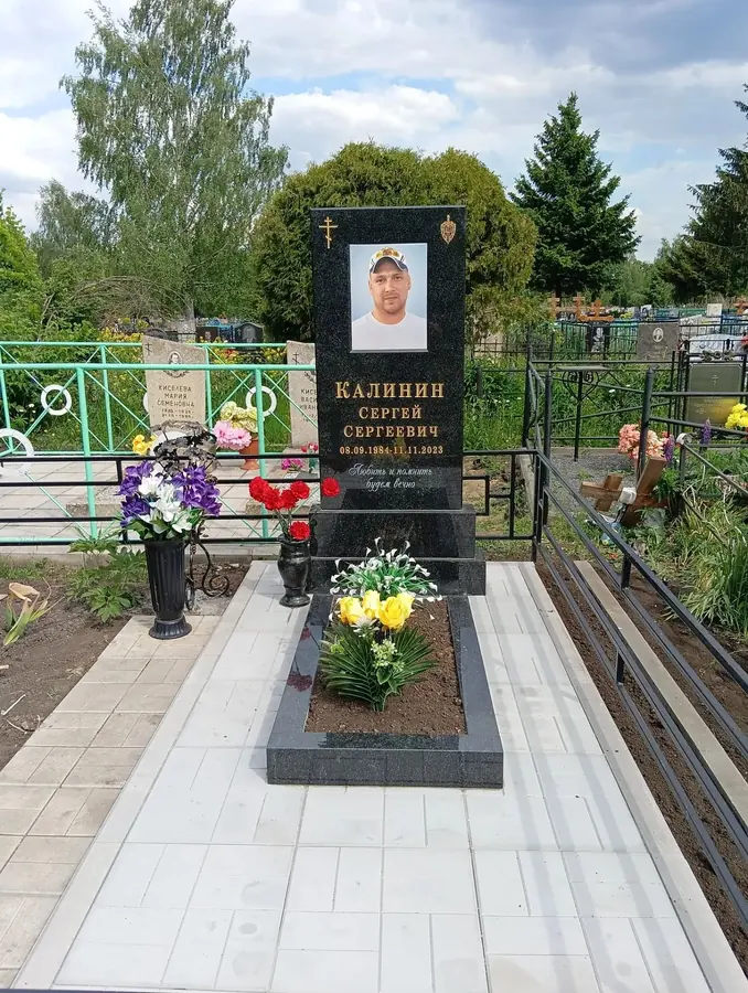 Одиночный чёрный памятник с портретом, цветником и светлой плиткой